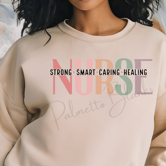 Beige sweatshirt with “NURSE” design in soft multicolor block letters and bold black text reading “Strong • Smart • Caring • Healing” across the chest.